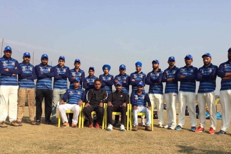 Indians in cricket uniforms stand as a team