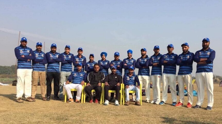 Indians in cricket uniforms stand as a team