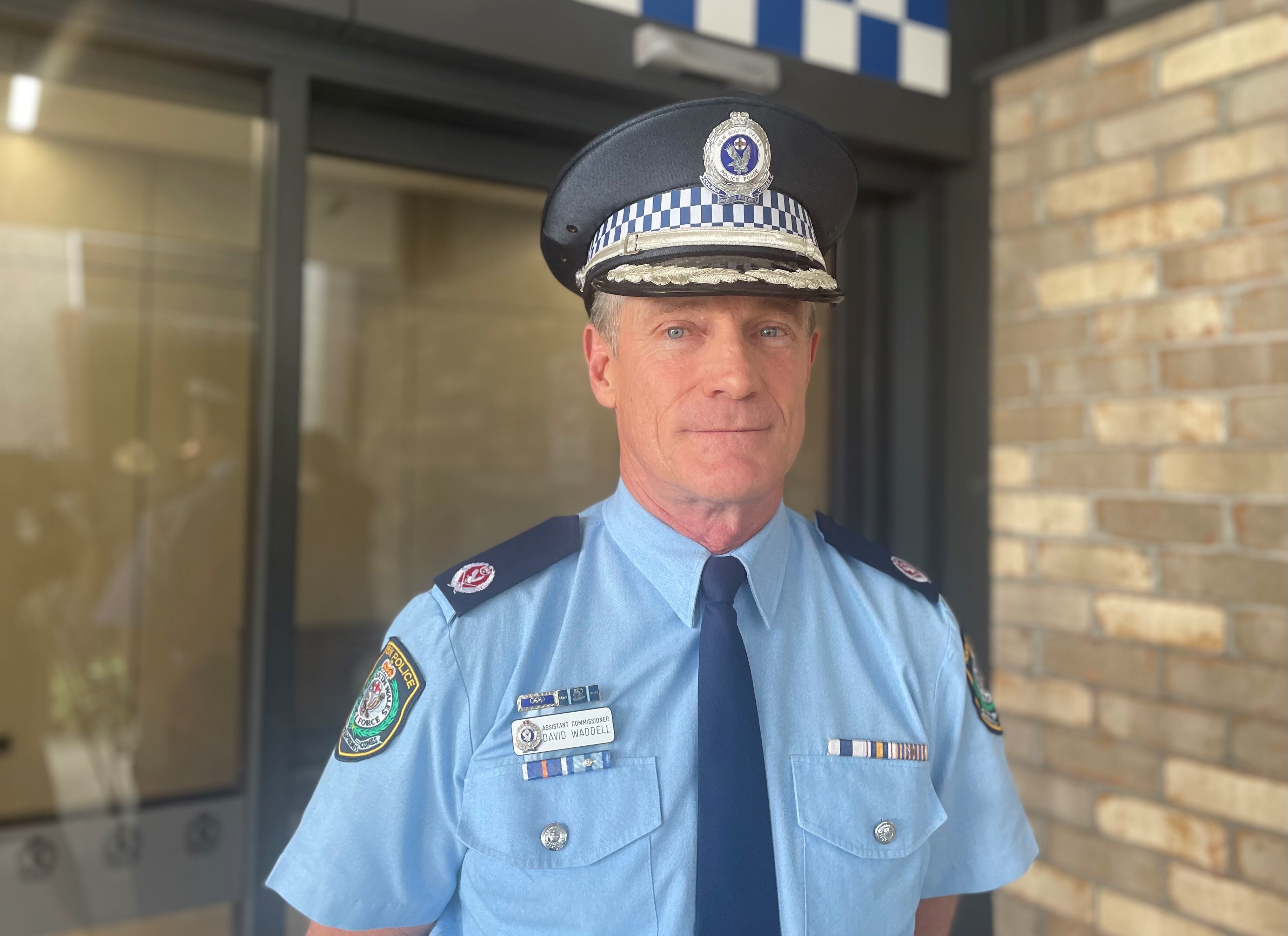 a senior police officer stands outside a police station