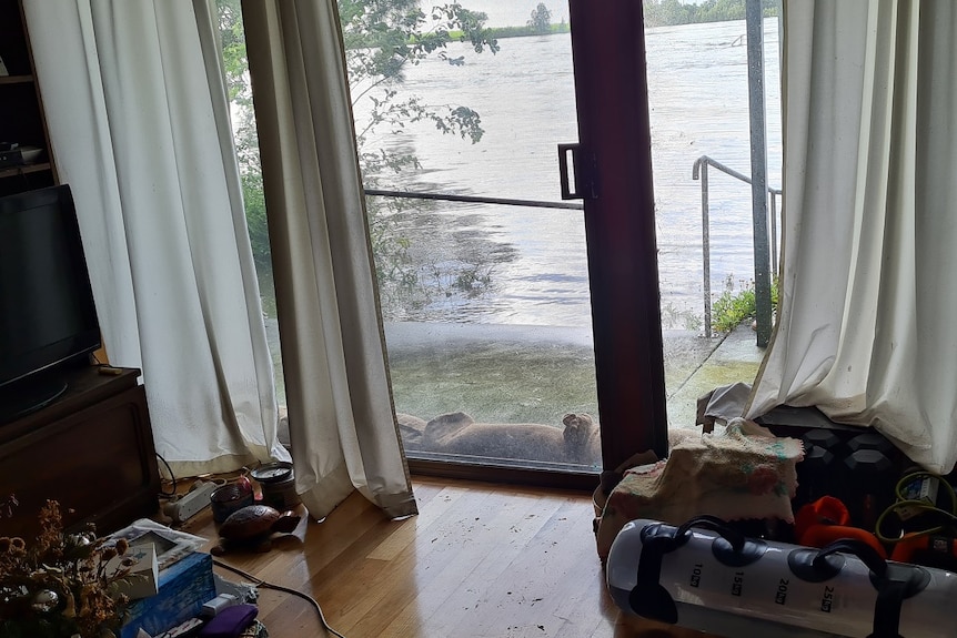 A timber floor and a sliding door with flood water just outside.