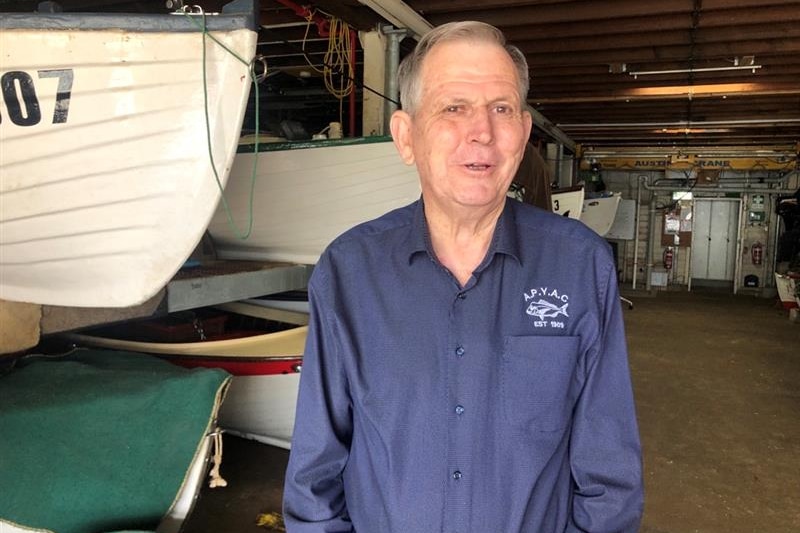 A man stands in a boat shed.