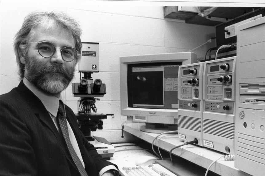 Alan Mackay-Sims at an old computer when he was younger with a beard.