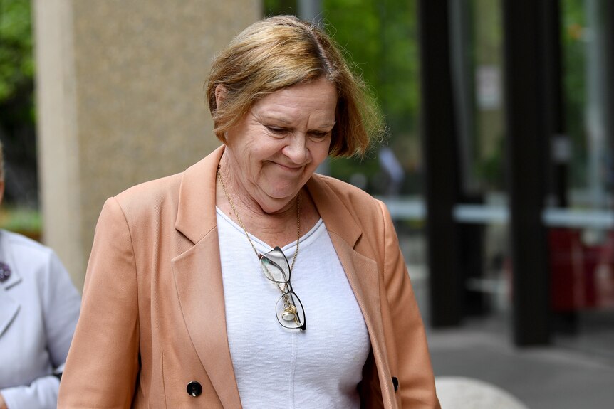 Susan Karpik wears a blazer and looks down toward the ground as she walks outside Sydney's Federal Court