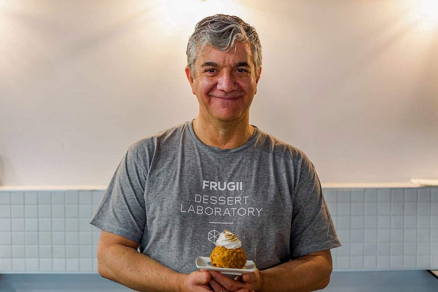 A man holding dessert smiles.