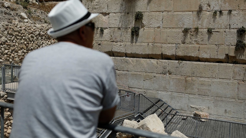 A man looks at the Western Wall, where stone fell off