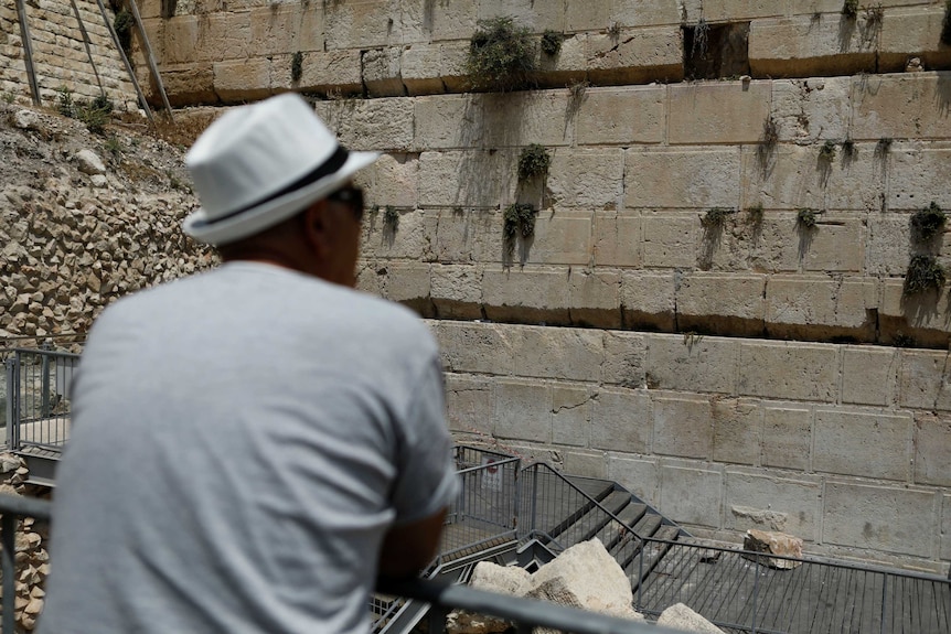 A man looks at the Western Wall, where stone fell off