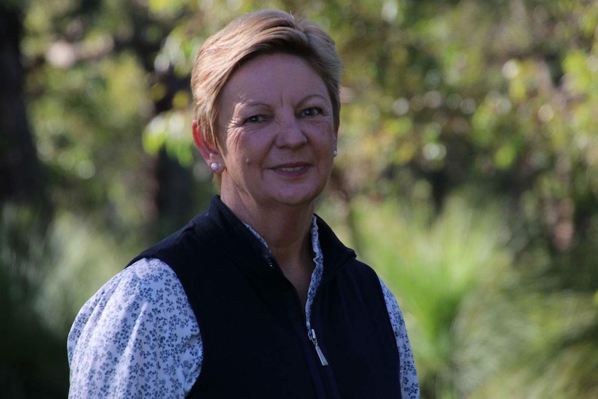 A close up of Kim Dravnieks in green bushland.