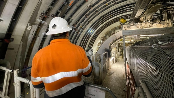 Worker in high vis standing next to a tunnel boring machine.