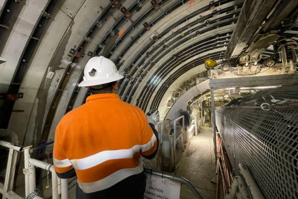 Worker in high vis standing next to a tunnel boring machine.