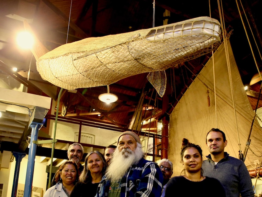Group of Aboriginal people with a sculpture of a whale made of reeds.
