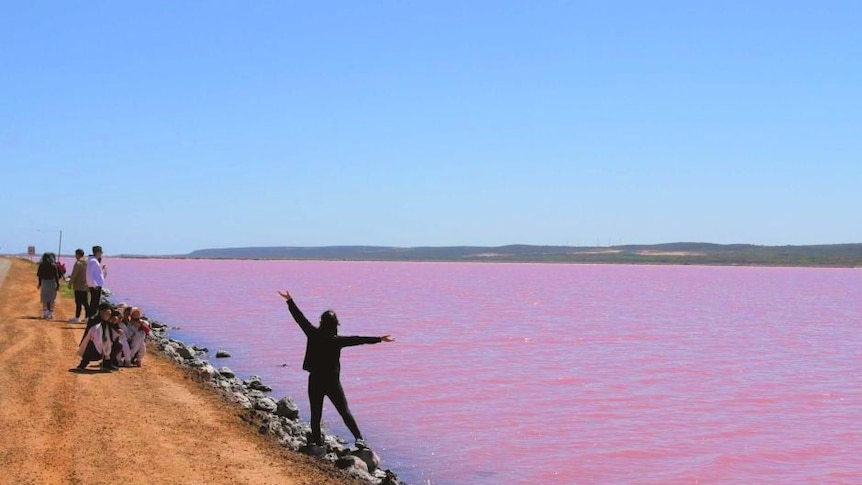 Chinese tourist poses for photo at the pink lake in Port Gregory
