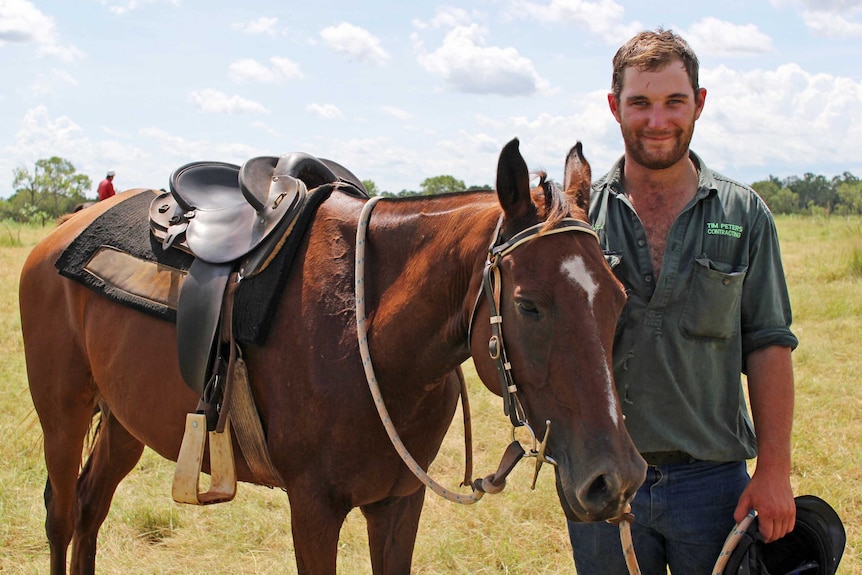 a man with a horse in a paddock.