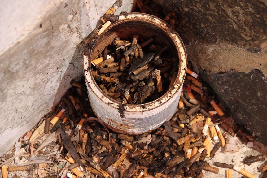 Cigarette butts around an old can