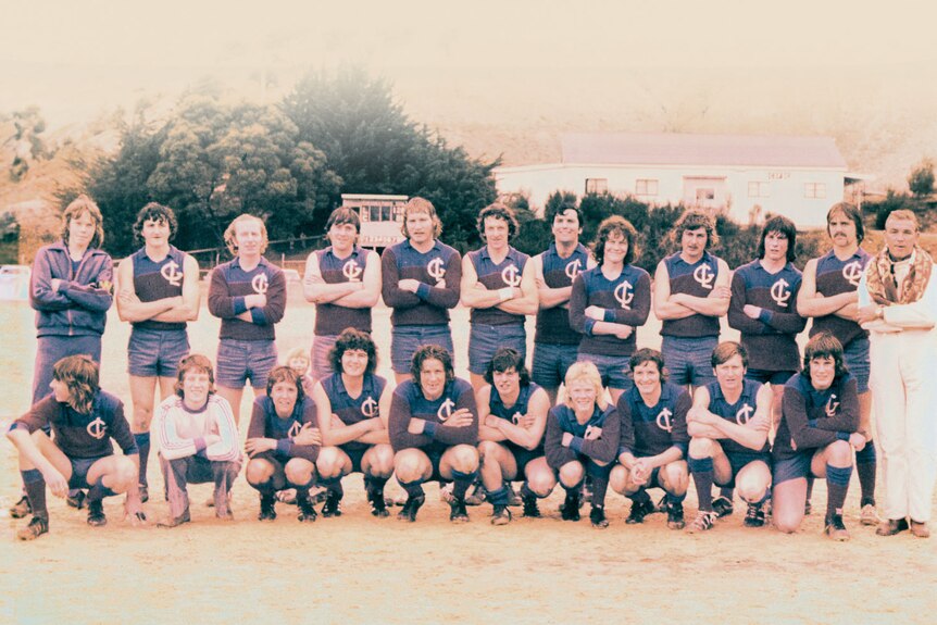 Football team shot on gravel oval, mid 1970s