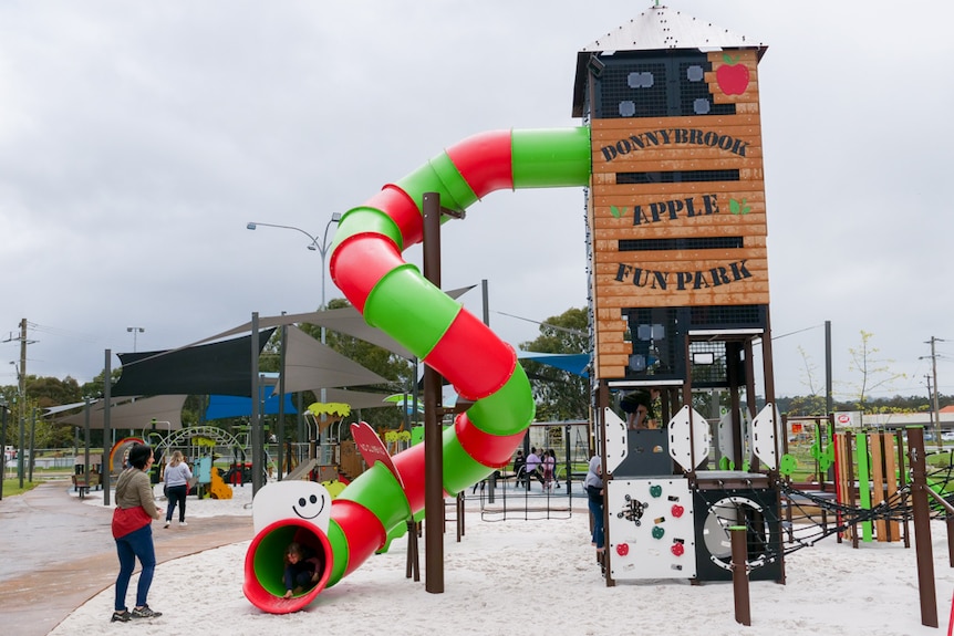 A wide shot of a playground with a large tower and colourful slide