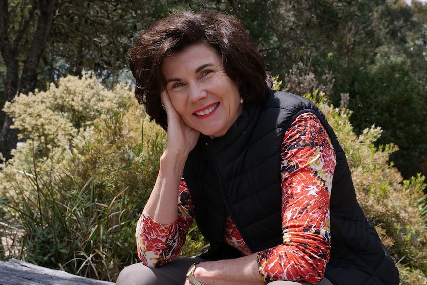 A woman sitting on a log looking at the camera