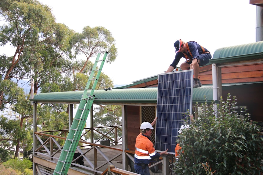 Workers install a solar panel
