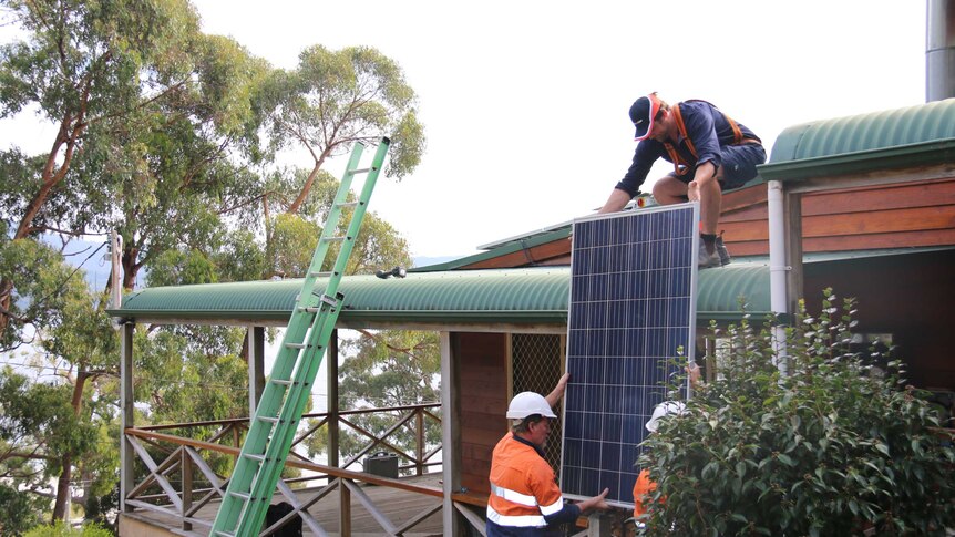 Workers install a solar panel