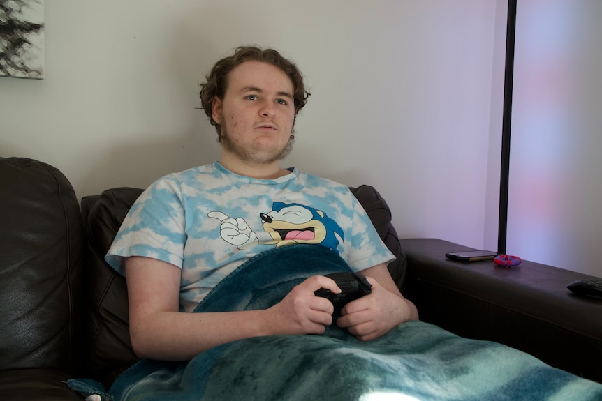 Teenage boy sitting on a couch playing video games.