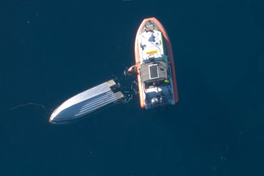 Aerial shot of a rescue boat and a capsized fishing boat.