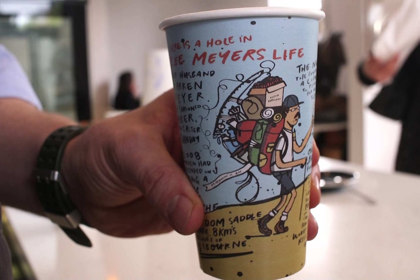 A person holds out an artistic coffee cup