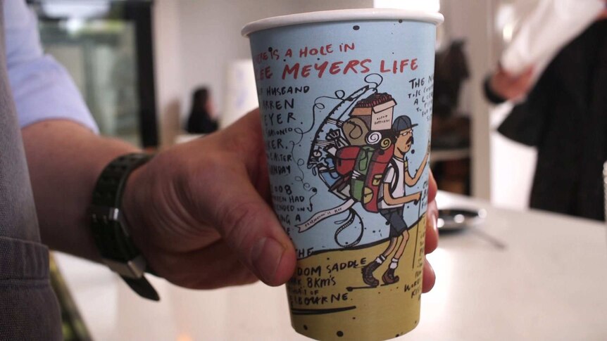 A person holds out an artistic coffee cup