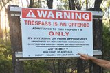 A no trespassing sign with a man wearing a cowboy hat