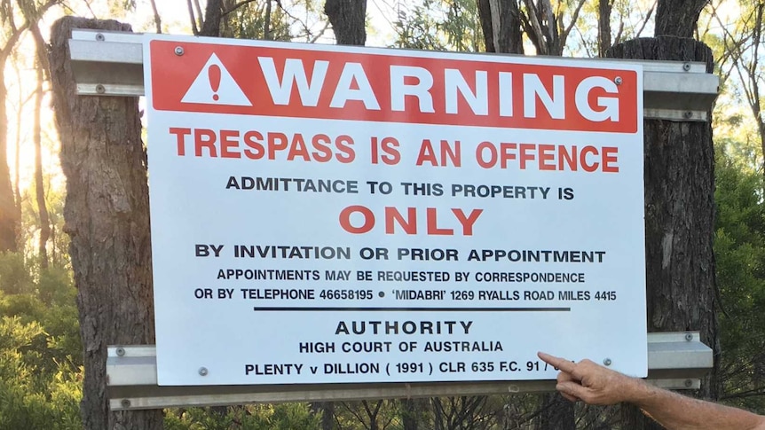 A no trespassing sign with a man wearing a cowboy hat
