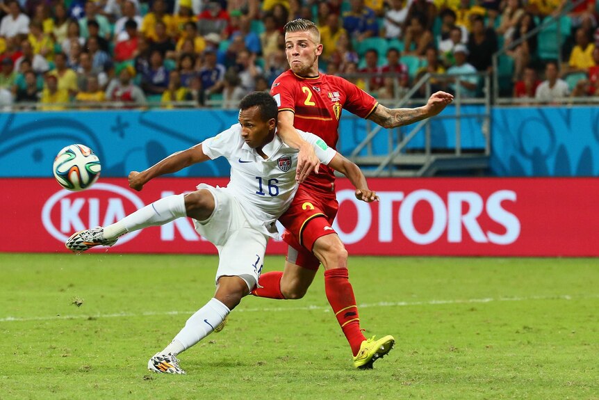 US player scores against Belgium in the 2014 FIFA World Cup with advertising in background.