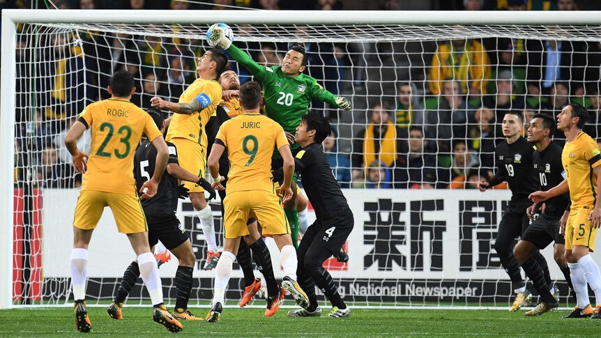 Tim Cahill rises for a header as the Thai keeper punches the ball away in a crowded penalty area.