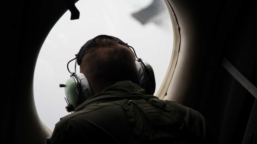 Crew member peers out window during MH370 search