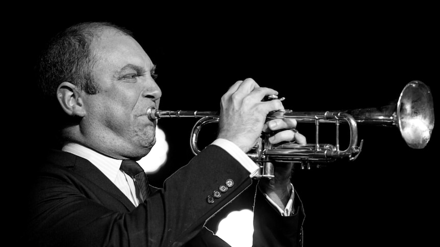 A monochrome photo of Mat Jodrell with his trumpet