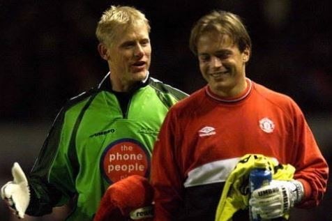 Two goalkeeping teammates have a laugh together at training.