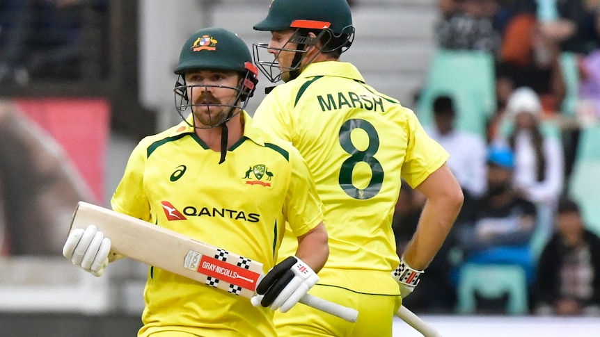 Australia batters Travis Head and Mitch Marsh run between wickets in yellow clothes during a Twenty20 game,