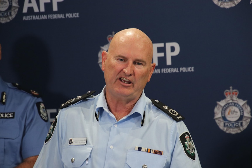 A male police officer addresses media while wearing an official uniform