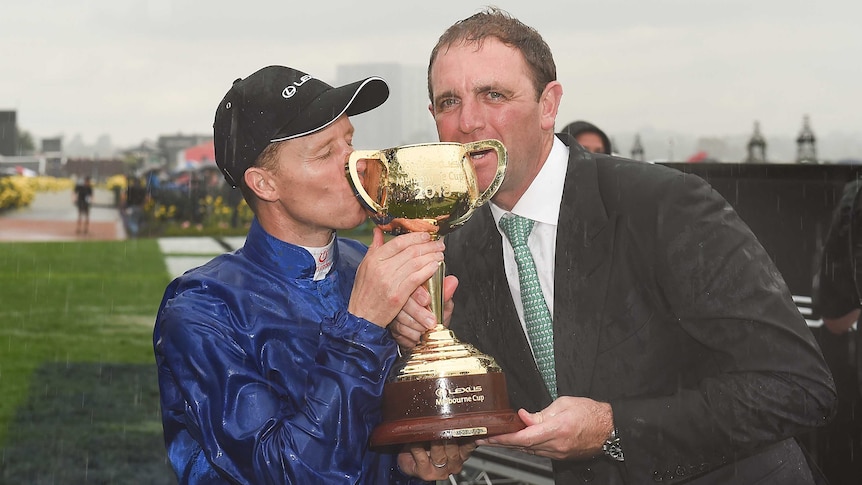 Kerrin McEvoy (L) and trainer Charlie Appleby kiss the Melbourne Cup trophy at Flemington.