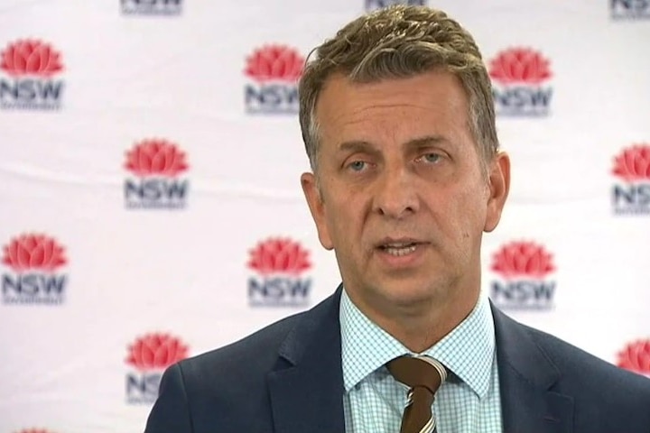 Profile of a man in front of NSW government logos.