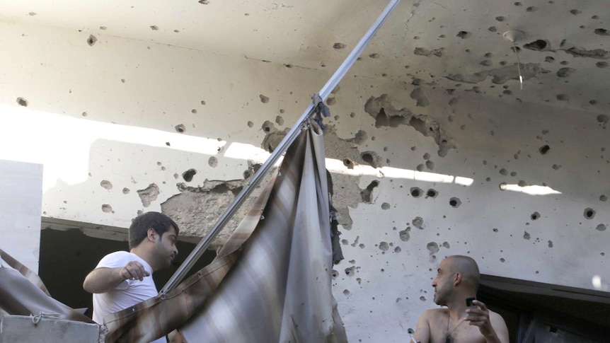 Two men inspect their damage house after two rockets hit their area in Beirut.