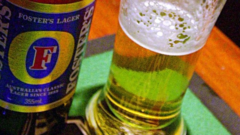 A Fosters beer sits on a bar