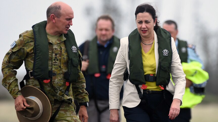 Queensland Premier Annastacia Palaszczuk walks while talking to Brigadier Christopher Field.