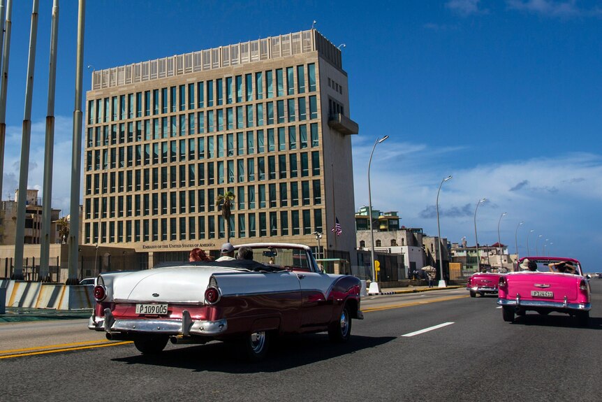 Tourists ride classic convertible cars on the Malecon beside the United States Embassy in Havana, Cuba