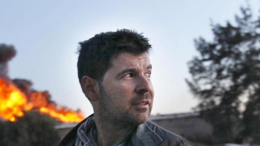 Getty Images photographer Chris Hondros stands in front of a burning building