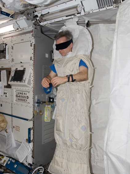 Dr Robert Thirsk lies upright in a sleeping bag.