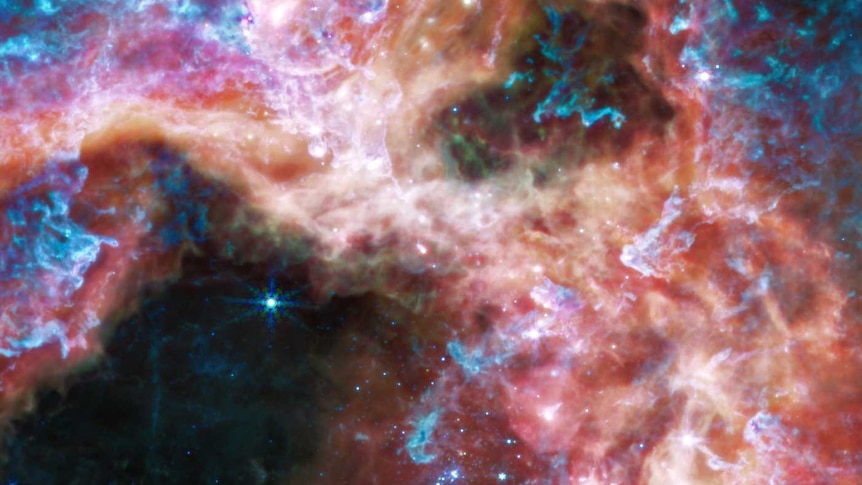 A vibrant, colourful image of a star cluster in a nebula full of stars, gas and cosmic dust.