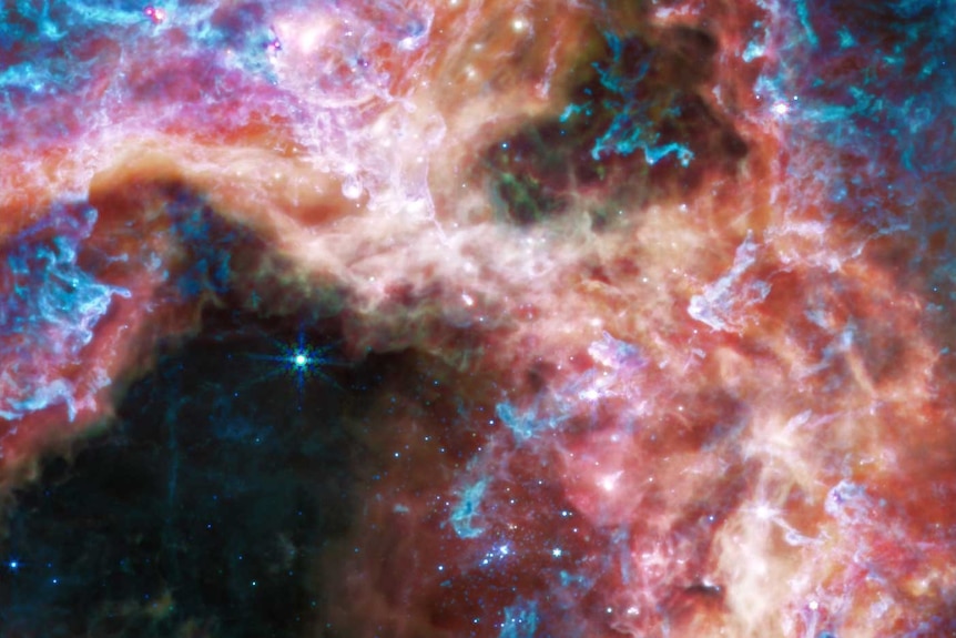 A vibrant, colourful image of a star cluster in a nebula full of stars, gas and cosmic dust.