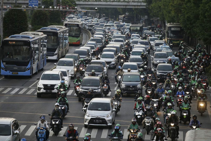 A six-lane highway choked with buses, cars and motorbikes all driving in the same direction.