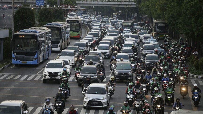 A six-lane highway choked with buses, cars and motorbikes all driving in the same direction.
