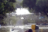 A man surveys the debris floating in the floodwaters