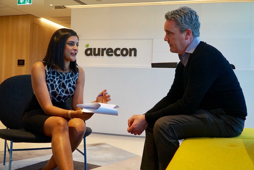 Mayuri Nathoo speaking to a colleague with Aurecon signage in the background.