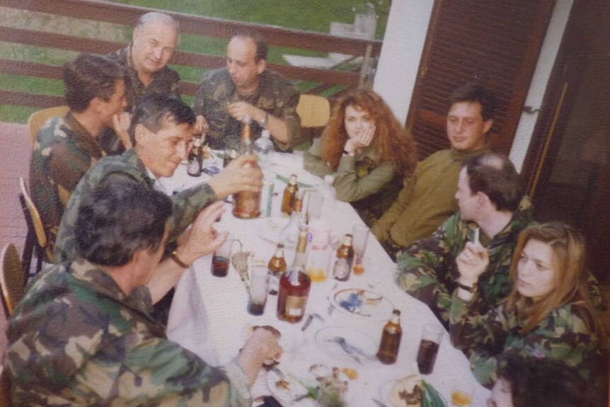 An archival photo of people in UN uniform sitting around a table, eating.
